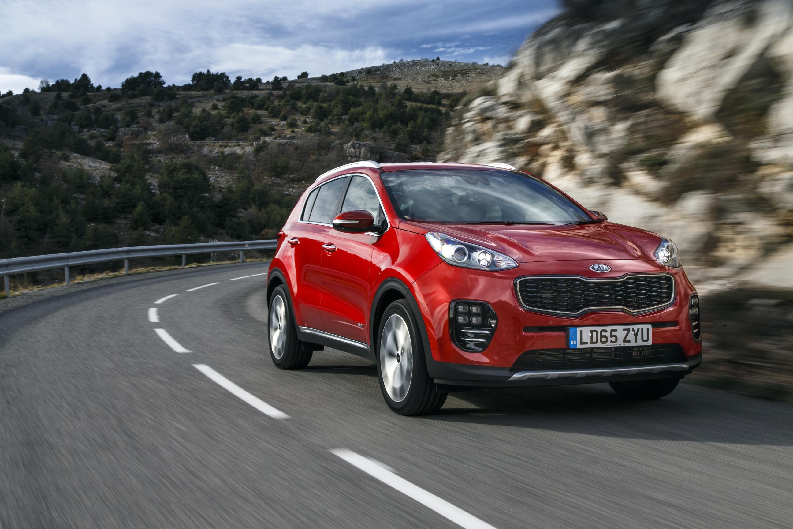 Red Kia Sportage driving towards the right on a mountain road